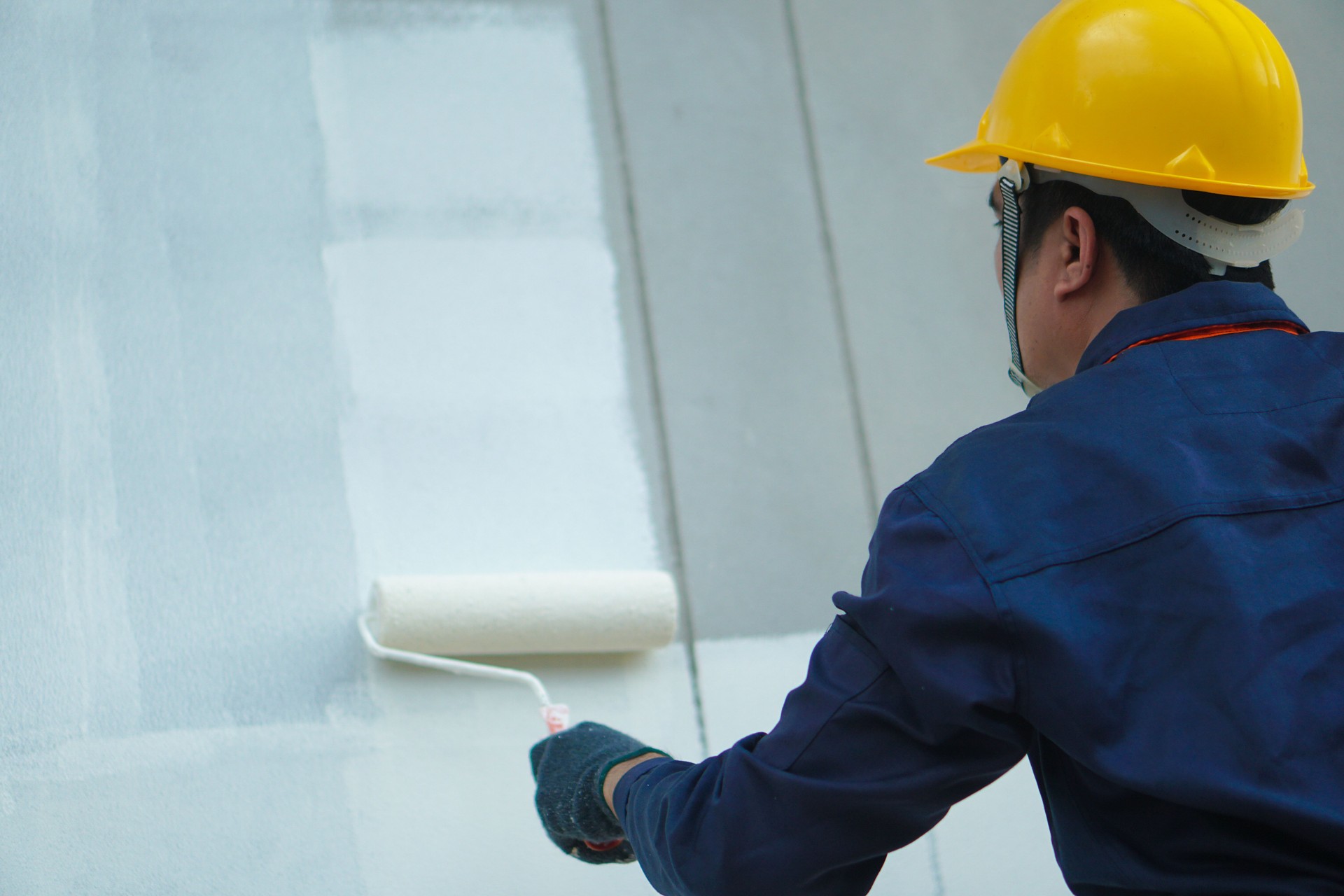 Asian construction worker painting the walls of a house outdoors